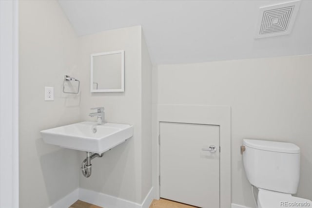 bathroom featuring lofted ceiling, sink, and toilet