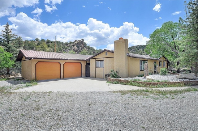 30600 County Road 371, Buena Vista, CO 81211 - view of front of house featuring a garage, a chimney, gravel driveway, and a metal roof