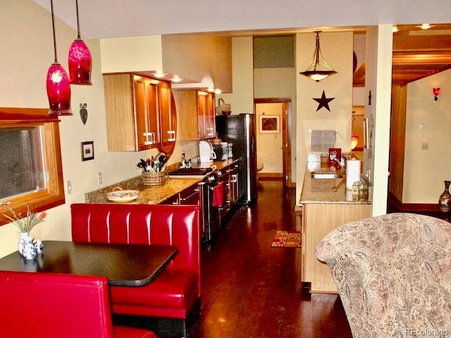 kitchen featuring black fridge, sink, light stone counters, a kitchen island, and dark wood-type flooring