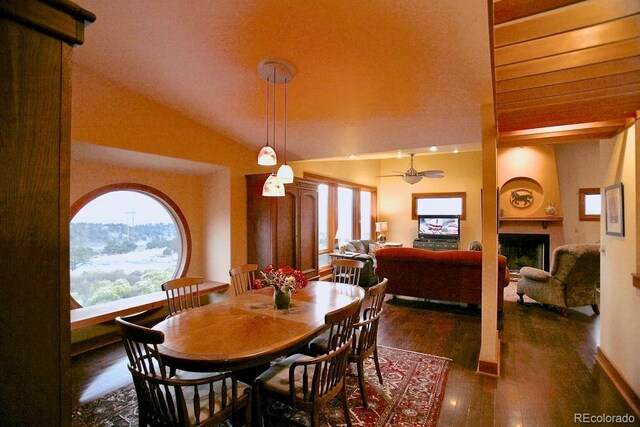 dining area with a large fireplace, ceiling fan, a mountain view, dark hardwood / wood-style floors, and lofted ceiling