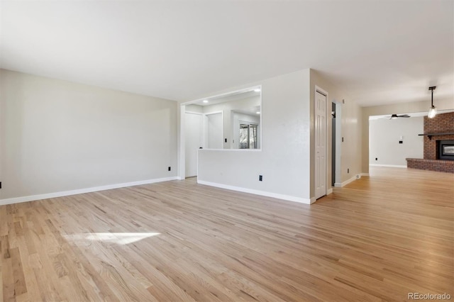 unfurnished living room featuring a fireplace, light wood-type flooring, and ceiling fan