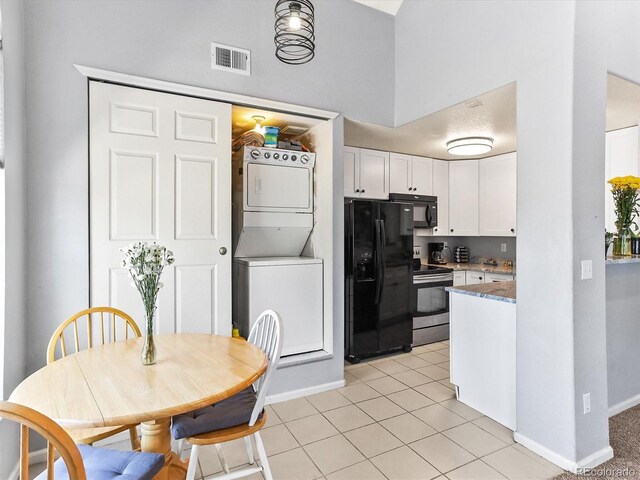 8361 S Upham Way Unit 209, Littleton, CO 80128 - kitchen featuring estacked washer and dryer, black appliances, white cabinetry, baseboards, and light tile patterned floors