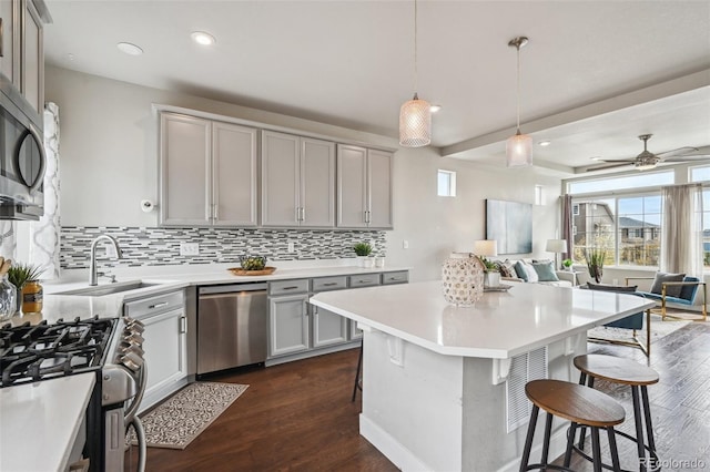 kitchen featuring appliances with stainless steel finishes, gray cabinets, a kitchen breakfast bar, and open floor plan