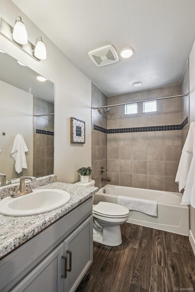 full bathroom featuring toilet, wood finished floors, shower / washtub combination, visible vents, and vanity