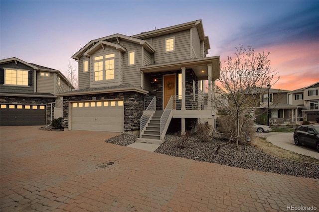craftsman inspired home featuring decorative driveway, covered porch, a garage, stairs, and stone siding