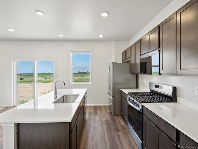 544 97th Ave, Greeley, CO 80634 - kitchen featuring appliances with stainless steel finishes, dark wood-type flooring, dark brown cabinets, a kitchen island with sink, and recessed lighting
