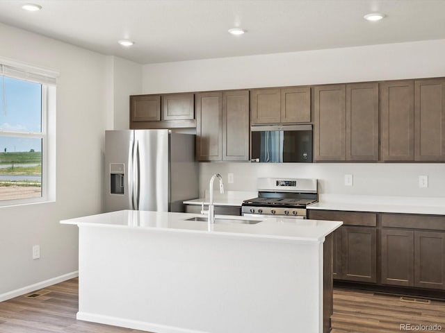 544 97th Ave, Greeley, CO 80634 - kitchen featuring stainless steel appliances, dark wood-style flooring, light countertops, a kitchen island with sink, and dark brown cabinetry