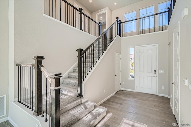 entryway featuring a towering ceiling, light hardwood / wood-style flooring, and plenty of natural light