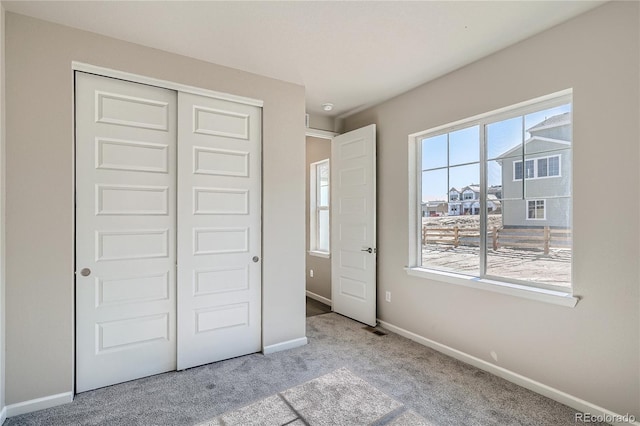 unfurnished bedroom with light carpet and a closet