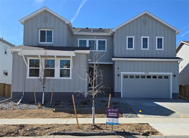 view of front of property featuring board and batten siding, concrete driveway, fence, and a shingled roof