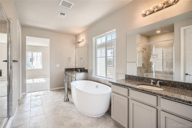 full bathroom featuring a stall shower, visible vents, a freestanding tub, and a sink