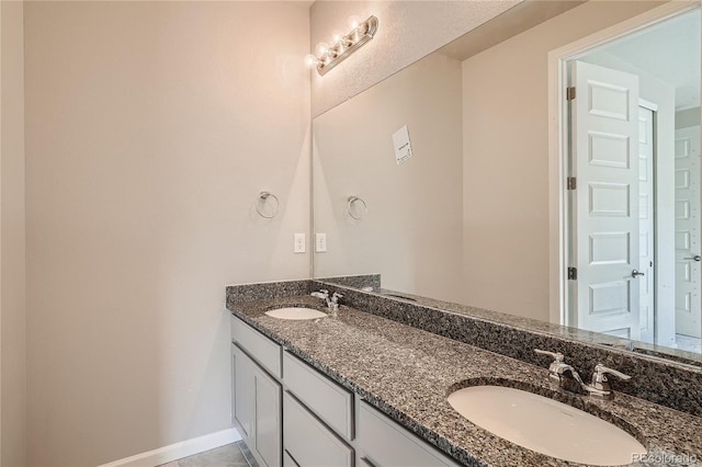 bathroom featuring a sink, baseboards, and double vanity