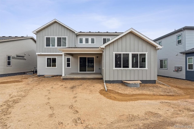 back of house with board and batten siding and a patio