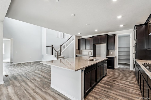 2560 Wesley Ln, Lafayette, CO 80026 - kitchen with light stone countertops, dark brown cabinets, a sink, wood finished floors, and a kitchen island with sink