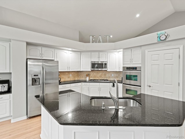 5497 W Prentice Ct, Littleton, CO 80123 - kitchen with appliances with stainless steel finishes, lofted ceiling, a large island, decorative backsplash, and light wood finished floors