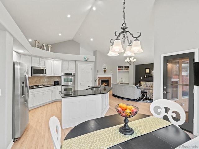5497 W Prentice Ct, Littleton, CO 80123 - dining area featuring light wood finished floors, high vaulted ceiling, a warm lit fireplace, a chandelier, and recessed lighting