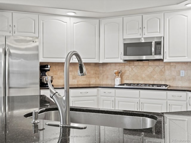 5497 W Prentice Ct, Littleton, CO 80123 - kitchen featuring stainless steel appliances, white cabinetry, dark stone countertops, and decorative backsplash