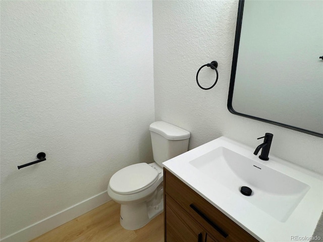 bathroom with hardwood / wood-style floors, toilet, and vanity