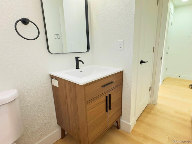 bathroom featuring wood-type flooring, toilet, and vanity