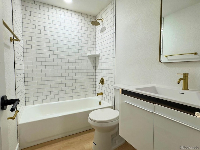 full bathroom with vanity, hardwood / wood-style flooring, tiled shower / bath, and toilet