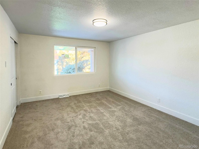 empty room featuring a textured ceiling and carpet