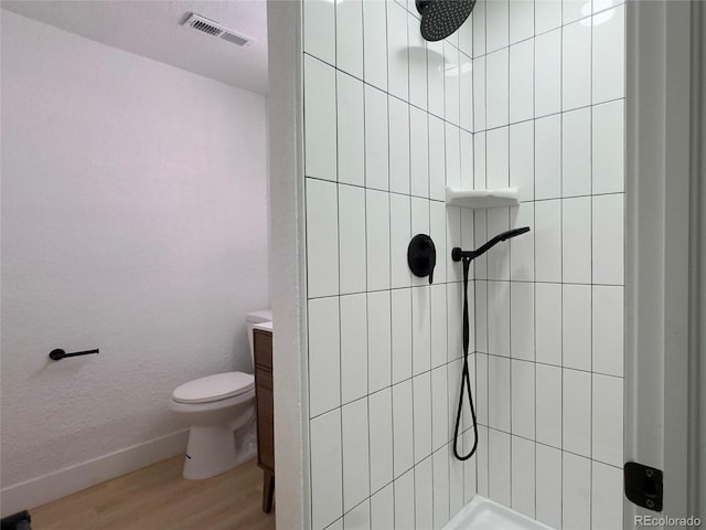 bathroom featuring toilet, tiled shower, and hardwood / wood-style flooring