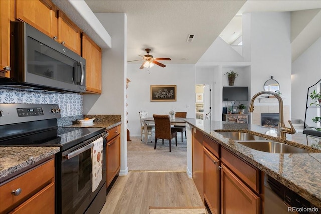 5378 Palomino Ranch Pt Unit 303, Colorado Springs, CO 80922 - kitchen with visible vents, a tile fireplace, dark stone countertops, stainless steel appliances, and a sink