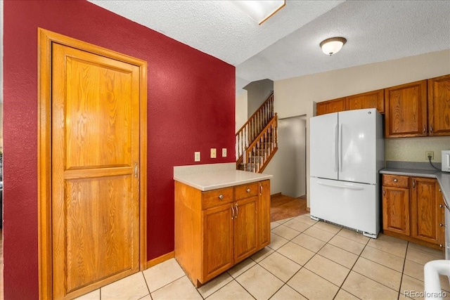 1345 2nd Street Rd, Eaton, CO 80615 - kitchen with a textured wall, brown cabinetry, white appliances, and light tile patterned flooring