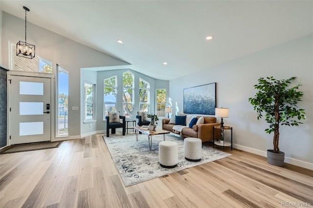 sitting room featuring high vaulted ceiling, light wood-type flooring, and a chandelier