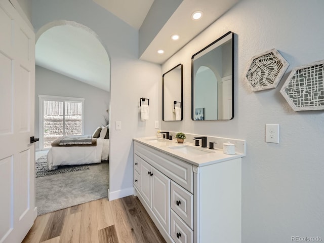 bathroom featuring hardwood / wood-style floors, vaulted ceiling, and vanity