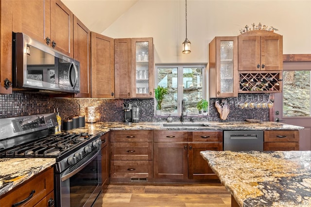 kitchen featuring appliances with stainless steel finishes, brown cabinetry, a sink, and light wood-style flooring
