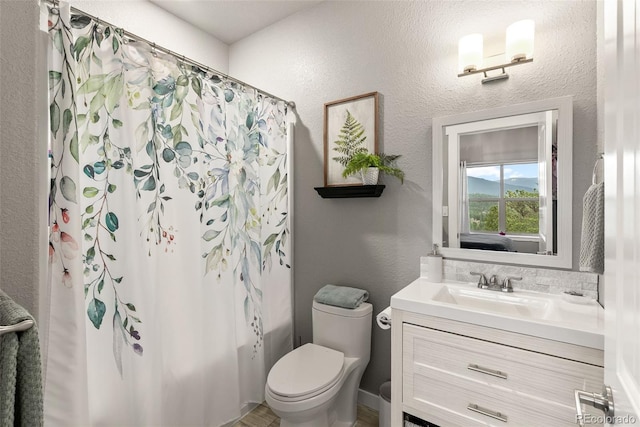 bathroom with vanity, a textured wall, shower / bath combo with shower curtain, and toilet