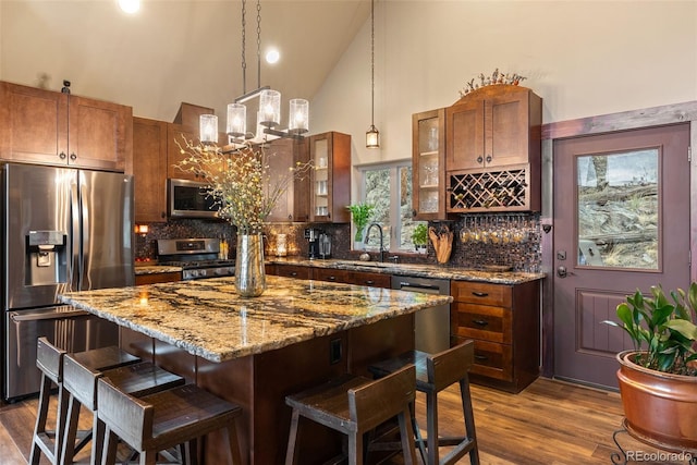 kitchen with a kitchen breakfast bar, high vaulted ceiling, appliances with stainless steel finishes, and tasteful backsplash