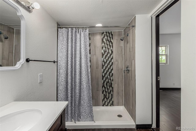 299 4th Ave, Limon, CO 80828 - bathroom featuring a stall shower, vanity, a textured ceiling, and wood finished floors