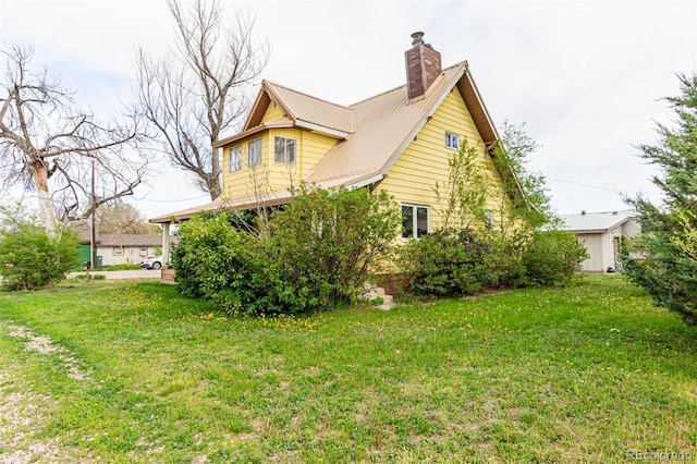 299 4th Ave, Limon, CO 80828 - view of home's exterior featuring a lawn, a chimney, and metal roof