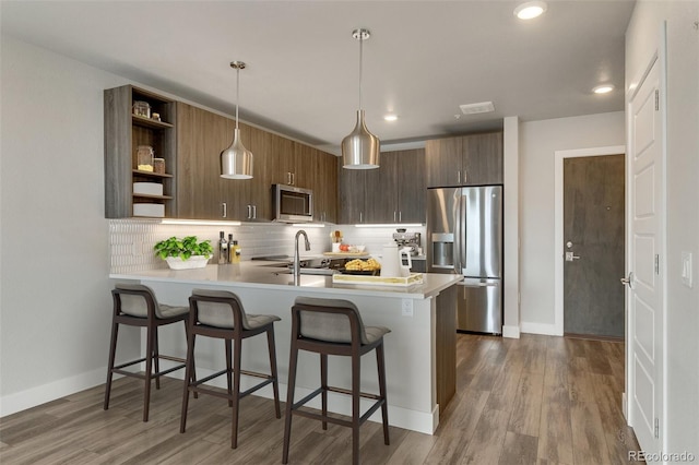 kitchen featuring pendant lighting, a kitchen breakfast bar, kitchen peninsula, and appliances with stainless steel finishes