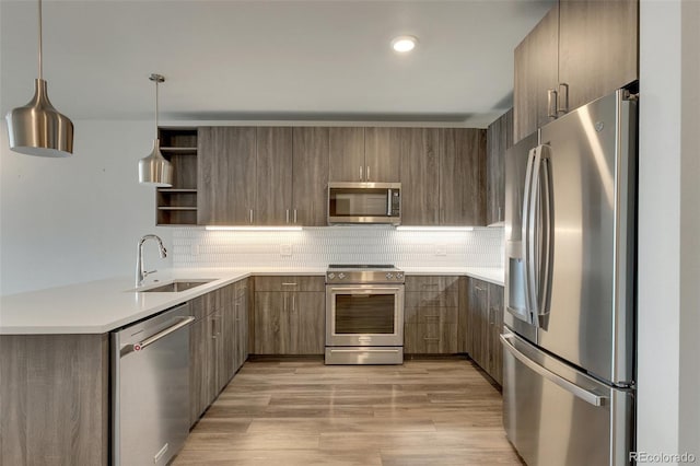 kitchen with sink, decorative backsplash, hanging light fixtures, and appliances with stainless steel finishes