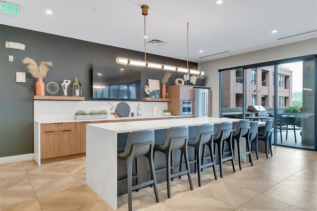 kitchen featuring a breakfast bar, decorative light fixtures, sink, a large island, and stainless steel appliances