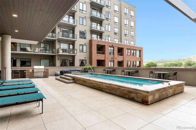 view of swimming pool with a grill, a mountain view, and a patio