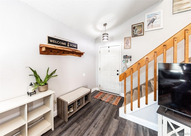 foyer entrance with dark wood-style flooring, a textured ceiling, stairway, baseboards, and lofted ceiling