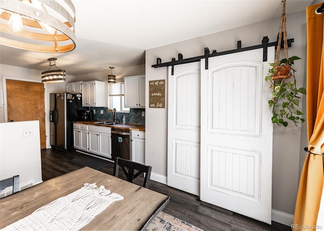 kitchen with tasteful backsplash, dark wood finished floors, a barn door, a sink, and stainless steel appliances