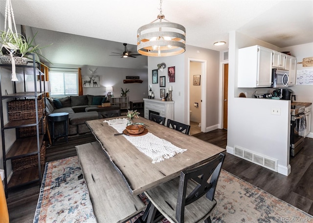 dining area with visible vents, dark wood finished floors, ceiling fan with notable chandelier, and baseboards