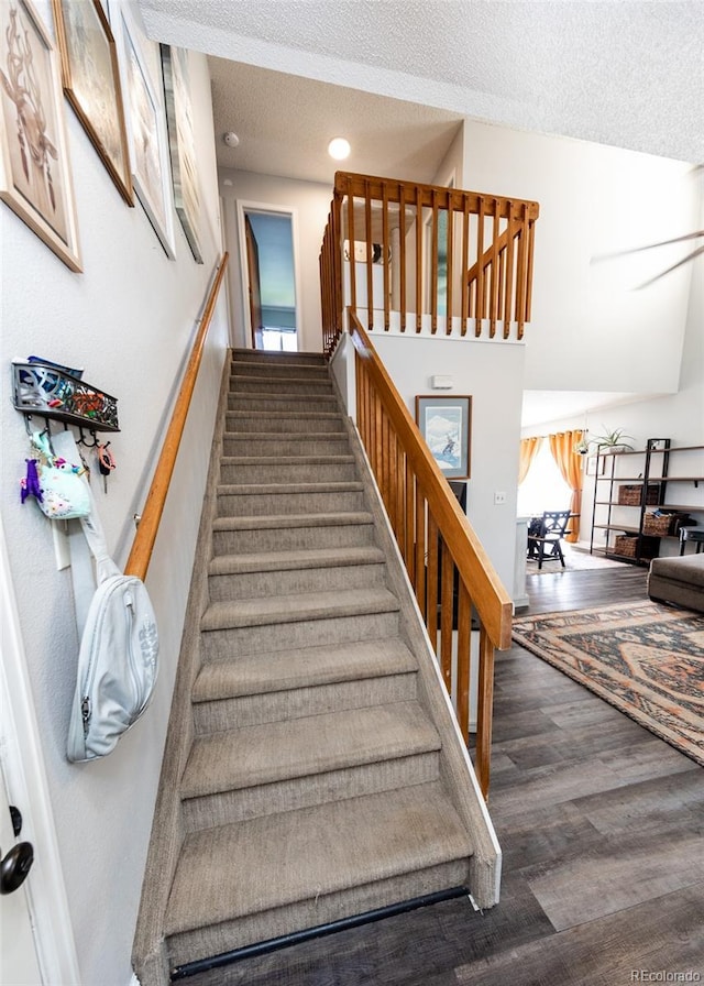 staircase featuring a textured ceiling and wood finished floors