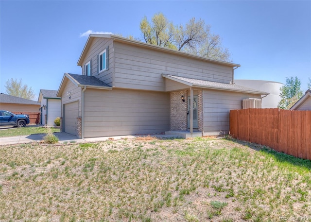 traditional home with a garage, fence, a front yard, and concrete driveway