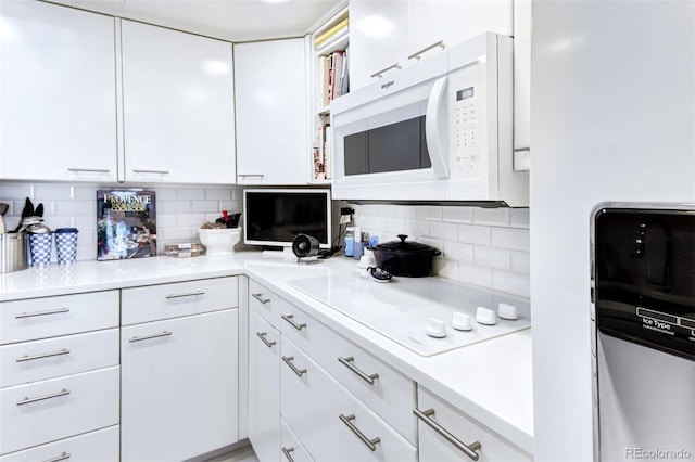 kitchen featuring refrigerator, backsplash, and white cabinetry