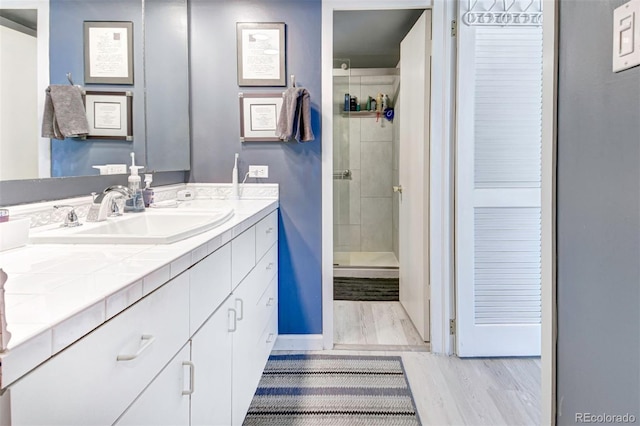 bathroom with vanity, tiled shower, and hardwood / wood-style floors