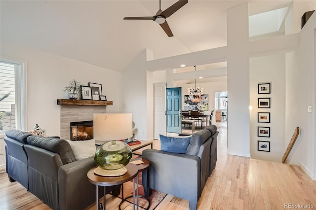 4565 E Mexico Ave Unit 3, Denver, CO 80222 - living room featuring ceiling fan, a tiled fireplace, light wood-type flooring, high vaulted ceiling, and a chandelier