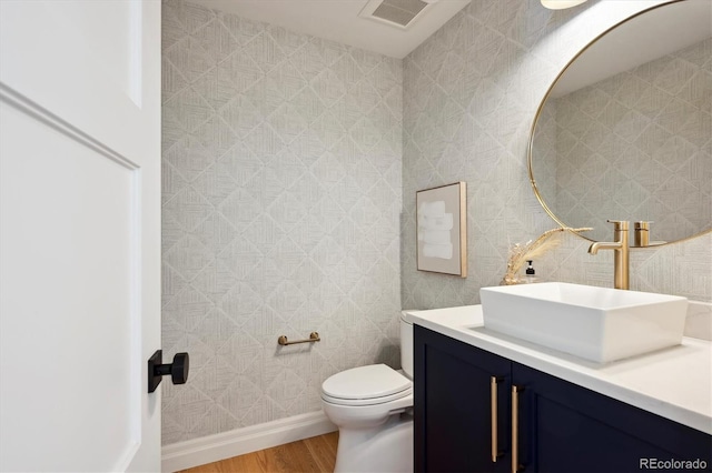 bathroom with visible vents, toilet, vanity, wood finished floors, and baseboards