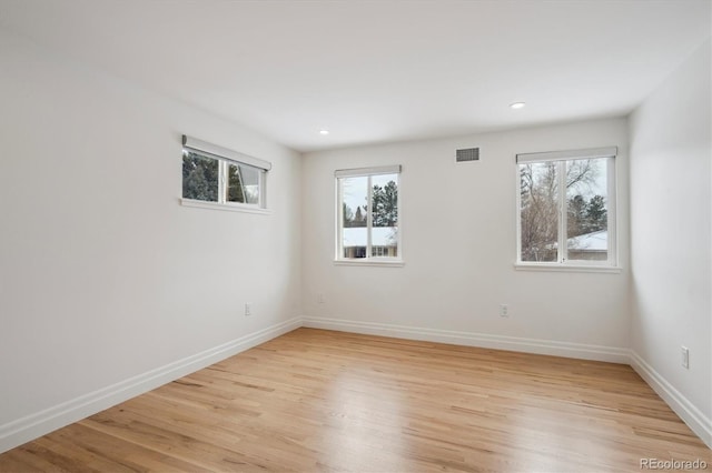 empty room featuring light wood-type flooring, visible vents, baseboards, and recessed lighting