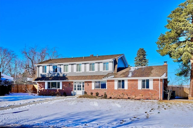 view of front of property with brick siding, a chimney, and fence